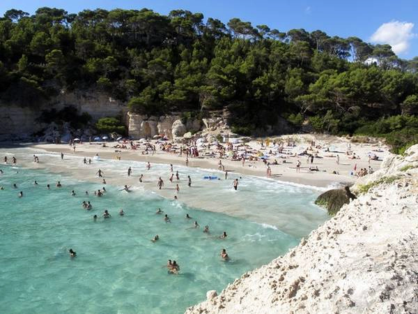 <strong>Cala Mitjaneta, Minorca, Tây Ban Nha: </strong>Bãi biển nhỏ nằm giữa các hang đá và vách núi này trở nên sôi động vào mùa hè. Ngoài việc nằm dài trên bãi cát, những du khách ưa mạo hiểm có thể lao xuống nước từ vách đá cao 9 m.