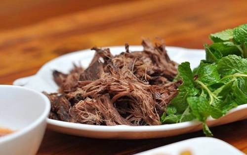 Thịt trâu gác bếpL Món ăn này vốn dĩ được chế biến bởi người Thái đen, nhằm dự trữ thực phẩm cho mùa mưa lũ hoặc những chuyến đi rừng dài ngày. Những mảng thịt thăn, thịt bắp được cắt dọc, ướp gia vị, lá rừng rồi treo lên gác bếp hun khói. Thịt trâu được hạ xuống sau 8 tháng đến một năm. Khói ám lâu ngày khiến thịt trâu có mùi hắc hơi khó ngửi, tuy nhiên càng nhai càng ngọt, từng thớ thịt cay thơm khiến những ai từng thưởng thức khó lòng quên được. Ảnh: foody