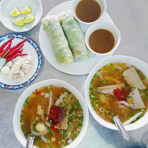 Bánh canh  Ở trung tâm Quy Nhơn, bạn sẽ dễ dàng bắt gặp quán bánh canh, nhưng được lòng nhiều thực khách bởi thâm niên và hương vị món ăn là quán ăn bà O trên đường Bạch Đằng. Nước dùng được ninh từ xương cá có vị ngọt và thơm đặc trưng. Bên trong món ăn còn có thêm cua ghẹ, tôm tươi, chả cá. Sợi bánh canh ở đây thon nhỏ, mềm mượt. Mỗi tô có giá trung bình 25.000 đồng, khách có thể gọi thêm đồ ăn kèm theo sở thích. Ảnh: Bùi Việt Anh.  Bún cộtMón ăn tại một quán vỉa hè trên đường Duy Tân kh