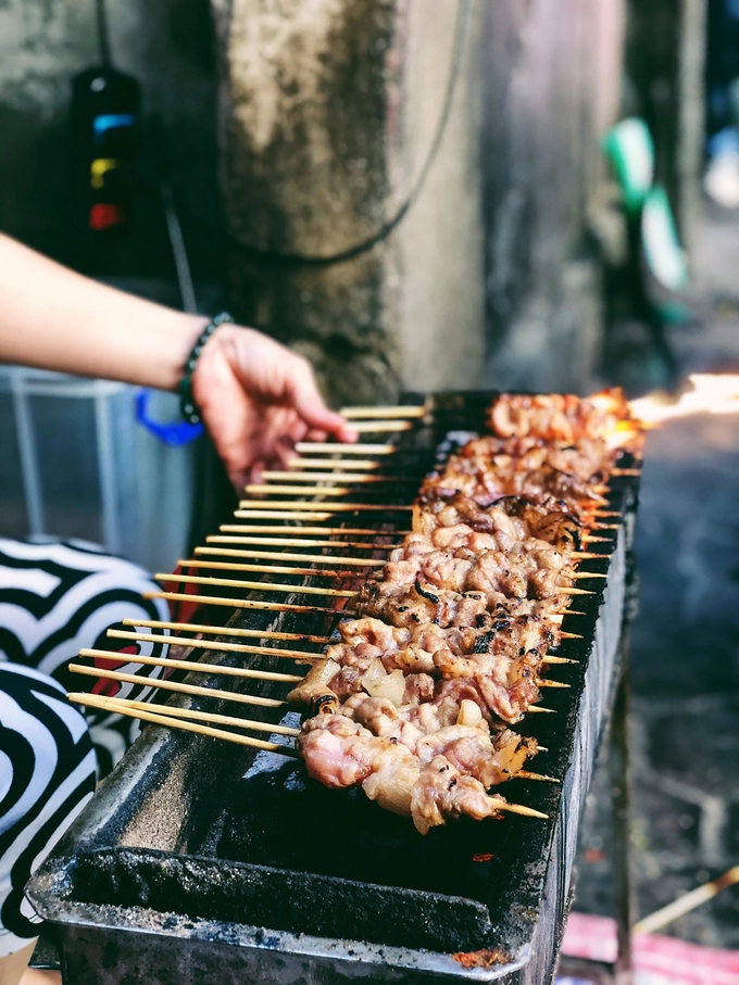 Thịt xiên nướng  Những quán thịt xiên nướng than hoa thơm lừng, xuất hiện như đốm lửa nhỏ nơi góc phố thủ đô trong những ngày xầm xì mưa rét. Đây là món ăn khoái khẩu của nhiều người, đặc biệt là giới trẻ và thường được thưởng thức vào giờ chiều. Lý do khiến món ăn hấp dẫn nằm ở khâu tẩm ướp riêng của mỗi quán để đem đến vị đậm đà trong từng thớ thịt bằng các gia vị như húng lìu, mắm cốt, hạt tiêu, mật ong... Thịt xiên nướng khi ăn sẽ chấm cùng tương ớt, có thể kèm theo bánh mì và rau húng đỏ.  Gợi ý địa chỉ: 18 Hàm Long, 127 Đặng Tiến Đông, 33 Quang Trung, 74 Ngọc Hà. Giá: 7.000 - 10.000 đồng một xiên, bánh mì 3.000 một chiếc. Ảnh: Thúy Anh.