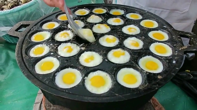 Trứng cút nướng được chế biến trong một khay lớn, có nhiều lỗ nhỏ giống như tổ ong. Món ăn nóng hổi, ăn không ngấy, du khách có thể tìm thấy ở nhiều quầy hàng trong các ngóc ngách ở chợ Chatuchak. Trứng cút nướng được chế biến trong một khay lớn, có nhiều lỗ nhỏ giống như tổ ong. Món ăn nóng hổi, ăn không ngấy, du khách có thể tìm thấy ở nhiều quầy hàng trong các ngóc ngách ở chợ Chatuchak.