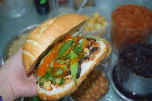 Bánh mì trộn: Nằm trong khu phố Tây Đề Thám, bánh mì trộn với phần nhân là nguyên liệu của món bánh tráng trộn, được rất nhiều người Việt và cả khách Tây ưa thích. Bánh mì cóc (loại bánh mì hơi tròn) nóng hổi, thơm giòn với đầy ắp khô bò đen, trứng cút chiên, tôm khô, chà bông, tóp mỡ và mỡ hành bên trong. Toàn bộ nguyên liệu do đích thân chủ quán chế biến với công thức riêng khiến một ổ bánh mì trộn đầy ắp nhưng không hề gây ngán. Giá một ổ là 18.00 đồng. Ảnh: Má Lúm.