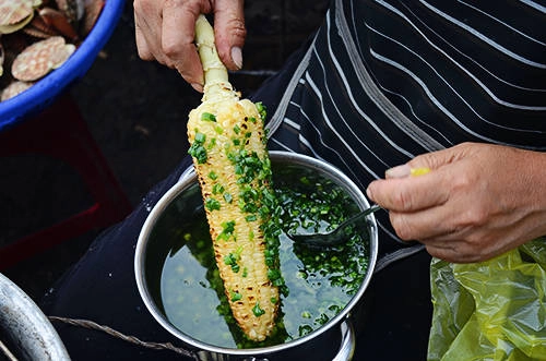 Bắp nướng mỡ hành Bắp nướng có được vị mặn ngọt vừa phải của mỡ hành, độ mềm dẻo của hạt chín tới, tạo nên món ăn vặt thú vị cho buổi chiều xứ mộng mơ. Món ăn này có mặt khắp nơi ở Đà Lạt, đặc biệt là quanh khu chợ Mới. Hàng quán không có gì đặc biệt ngoài chiếc bếp than, một chiếc giỏ để nguyên liệu và vài vật dụng chế biến. Khách thường mua mang đi chứ không ngồi ăn tại chỗ. Giá cho một trái bắp nướng khoảng 10.000 đồng. Ảnh: Phong Vinh.