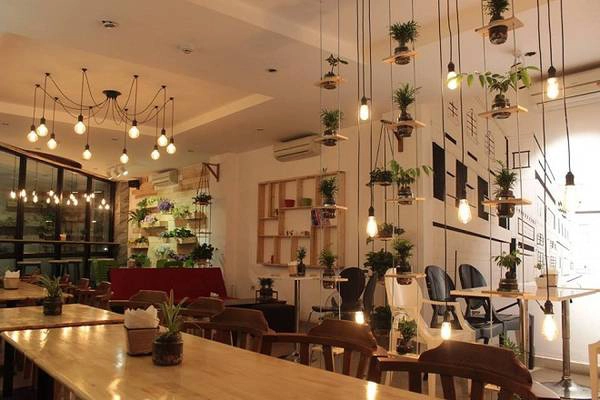 Green Coffee: Đúng như tên gọi, quán có cây xanh ở khắp nơi, từ lối đi, lan can cầu thang đến ô cửa sổ. Những chậu cây còn được bố trí trên những giá sách treo tường. Những chiếc bình thủy tinh cũng được tận dụng để trồng cây. Chủ quán kết hợp khéo léo giữa ánh sáng, màu sắc, bàn ghế và cây xanh, tạo nên không gian vừa hiện đại vừa gần gũi. Địa chỉ: số 8 ngõ Hàng Cháo, quận Đống Đa. Ảnh: Green Coffee.