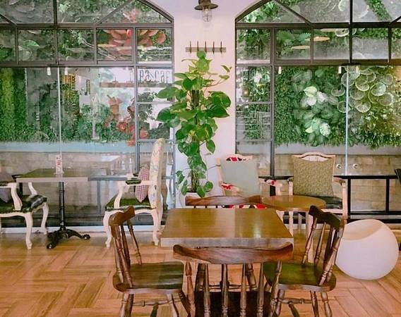 Cora Cafe: Quán có diện tích khá lớn, gồm 2 tầng, không gian thoáng đãng với những ô cửa lớn khiến nơi đây lúc nào cũng tràn ngập ánh sáng. Những thảm cỏ xanh độc đáo trên tường, cây đặt ở nhều góc, cầu thang gỗ tạo hình xoắn ốc nối giữa 2 tầng… là điểm thú vị của không gian nơi đây. Ngoài ra, quán còn có nhiều bức tranh tường theo nghệ thuật Typography đầy sáng tạo. Địa chỉ: 24 Hòa Mã. Ảnh: Cora Cafe.