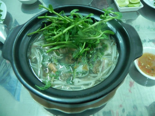 Bún cá thố: Thay vì những chiếc tô truyền thống, bún cá đặt trong thố đen đậy nắp, bên trong nước lèo vẫn còn sôi nhè nhẹ. Bún cá thố được ăn kèm rau đắng và giá. Bạn có thể thưởng thức ở quán bình dân trên đường Lâm Văn Bền, quận 7 với giá 30.000 đồng một thố. Ảnh: Thảo Nghi.