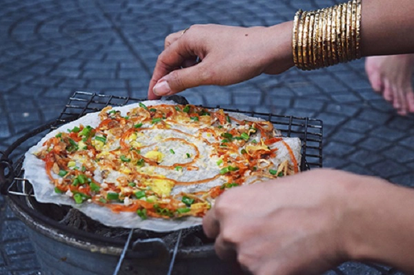 Bánh tráng nướng  Vị cay của ớt, giòn tan của chiếc bánh tráng cộng thêm các hương vị khác nhau của trứng cút, hành lá, trứng gà, xúc xích, thịt xay, khô bò,... tạo nên chiếc bánh đầy màu sắc và hấp dẫn. Từ 15.000 đến 30.000 đồng, bạn có thể thưởng thức một chiếc pizza với các loại vị khác nhau như: bánh tráng trứng phô-mai, bánh tráng trứng bò phô mai xúc xích, bánh tráng trứng phô mai gà xé, bánh tráng bánh dẻo,...  Địa chỉ gợi ý: đường Cao Thắng (quận 3). Ảnh: Má Lúm.