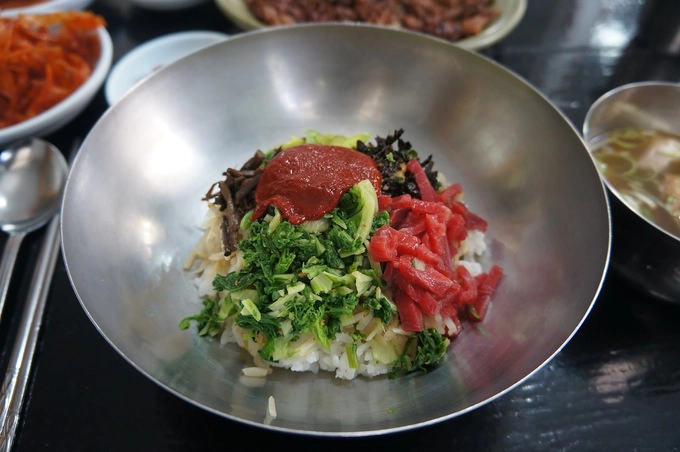 Cơm trộn yukhoe (thịt bò sống) gồm yukhoe, tảo biển khô, tương ớt cùng một vài nguyên liệu khác trộn chung với nhau cho vị vừa béo, vừa cay ăn khá lạ miệng. Cơm thường được làm nóng, đựng trong thố đá hoặc nhuôm dày để khi trộn lên, thịt bò có thể chín tái. Đây là một trong những món khá đặc trưng ở xứ củ sâm mà bạn khó có thể tìm thấy ở nơi nào khác.  Địa chỉ gợi ý: Cheonhwang, 3 Chokseok-ro207 beon-Gil, Jinju, Gyeongsangnam-do.