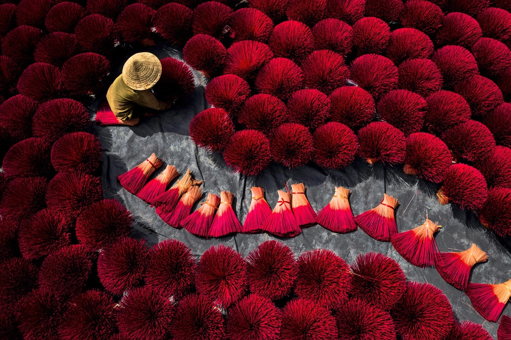 Ở ngoại ô Hà Nội, hình ảnh người lao động được bao quanh bởi các bó nhang đỏ tạo thành cảnh tượng ma mị, đầy sức hút. Ảnh: Thach Pham Ngoc.