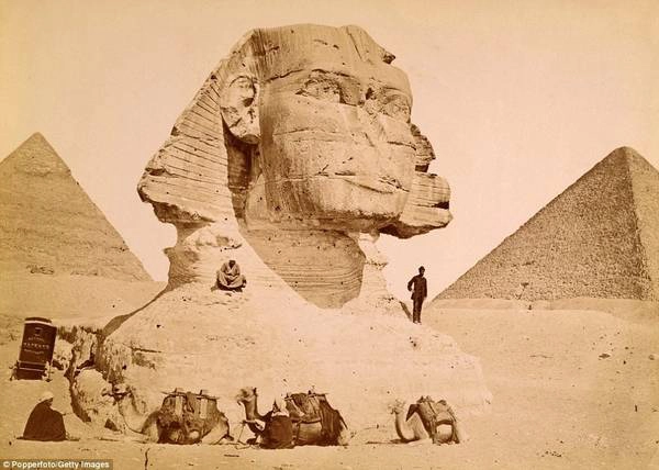 Một nam du khách đứng trên vai bức tượng nhân sư ở Giza năm 1890. Bên trái là kim tự tháp Kephren và bên phải là kim tự tháp Kheops. Ảnh: Pepperfoto/Getty.