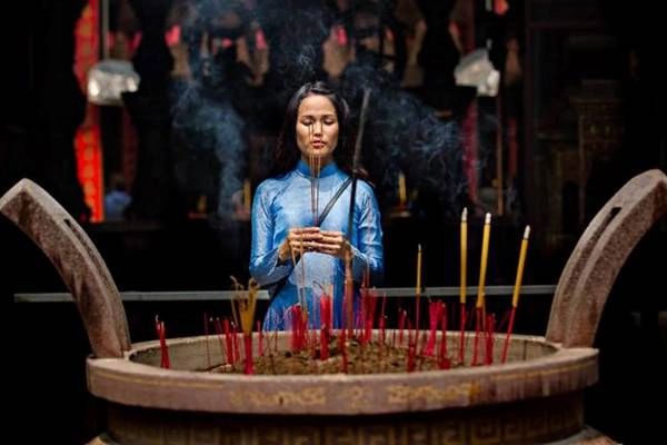 Khoảnh khắc cô gái với tà áo dài đang thắp hương cầu nguyện trong một ngôi chùa cổ kính ở Sài Gòn.