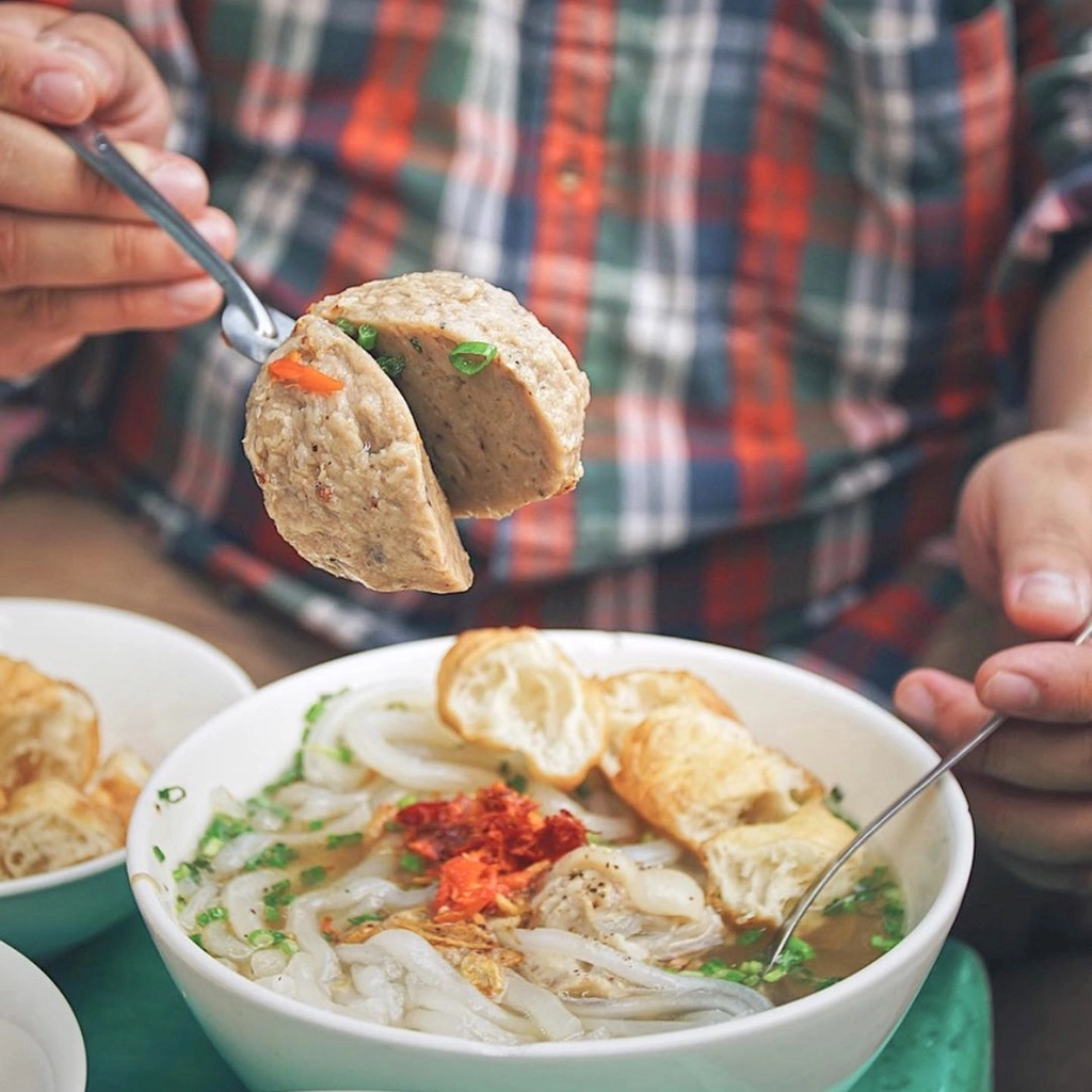 Hàng bánh canh bò viên trên đường Nguyễn Văn Nguyễn, quận 1, thu hút tín đồ sành ăn nhờ nhân bò viên khổng lồ lạ mắt, đượm hương tiêu. Sợi bánh canh có độ dai vừa phải. Thịt heo xắt lát quyện nước dùng nóng hổi tạo phiên bản ẩm thực thơm ngon. Ảnh: Foodholicvn.