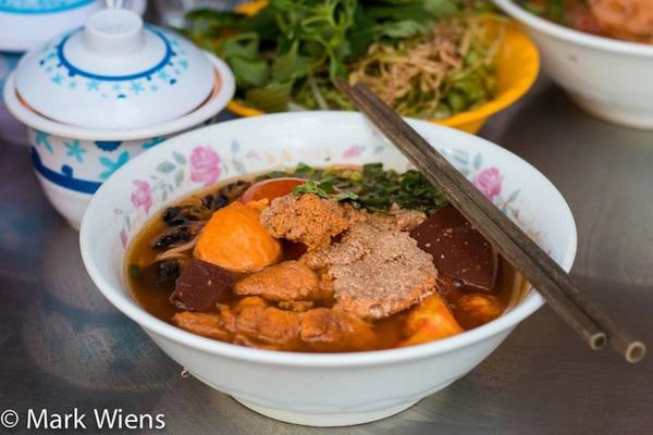 Bún riêu Sau khi thử nhiều món ở Sài Gòn, Mark Wiens thừa nhận anh đã thay đổi cách nhìn về ẩm thực của mình và bún riêu là món ăn mà anh rất yêu thích. Nước dùng nấu từ riêu cua và cà chua tạo mùi vị tự nhiên. Sợi bún mềm dai cũng góp phần cho món ăn thêm ngon miệng. Bát bún riêu còn có thêm đậu phụ rán vàng, tiết heo, chả cua, đôi khi có cả thịt viên. Địa chỉ gợi ý: Bún riêu đường Nguyễn Cảnh Chân. Bún riêu Sau khi thử nhiều món ở Sài Gòn, Mark Wiens thừa nhận anh đã thay đổi cách nhìn về ẩm thực của mình và bún riêu là món ăn mà anh rất yêu thích. Nước dùng nấu từ riêu cua và cà chua tạo mùi vị tự nhiên. Sợi bún mềm dai cũng góp phần cho món ăn thêm ngon miệng. Bát bún riêu còn có thêm đậu phụ rán vàng, tiết heo, chả cua, đôi khi có cả thịt viên. Địa chỉ gợi ý: Bún riêu đường Nguyễn Cảnh Chân.
