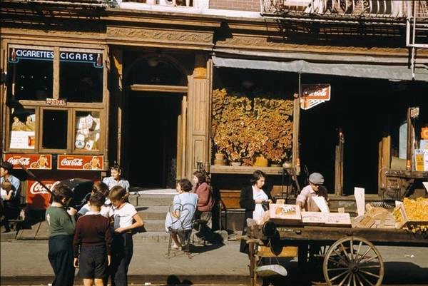 Trẻ em và người lớn vui chơi và trò chuyện ở các vỉa hè của phố Broome và Baruch Place, cũng thuộc Lower East Side.