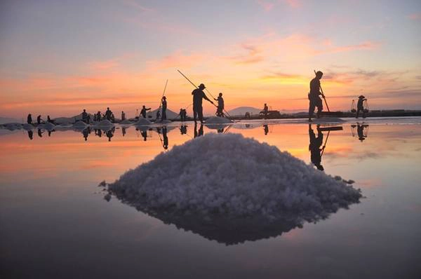 Bầu trời hừng lên trên cánh đồng muối Hòn Khói (Ninh Hòa). Trông từ xa, cánh đồng như một tấm gương lớn phản chiếu ánh bình mình và cả dáng những diêm dân một nắng hai sương. Ảnh: Trần Quí Thịnh.
