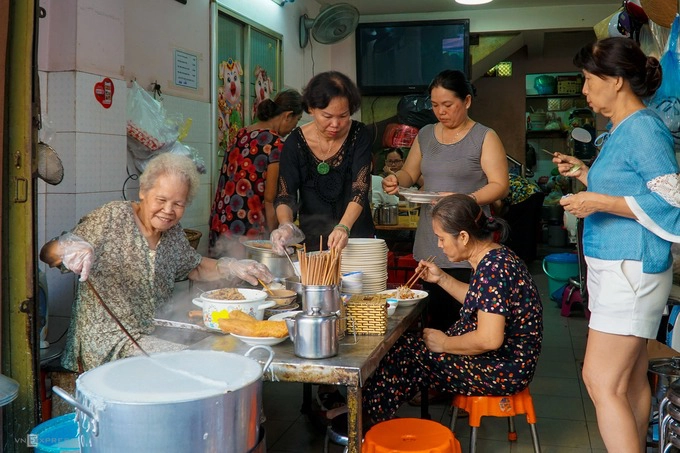 Lối nhỏ quanh co dẫn vào các khu chợ có nhiều quán ăn ngon. Một trong số đó là quán bánh cuốn của cụ bà Triệu My Thầu (ngoài cùng bên trái) giữa lòng chợ Bàn Cờ, quận 3.  Là người Lạng Sơn nhưng món bánh cuốn của cụ bà được làm theo kiểu miền Nam, với phần nhân xào thập cẩm ăn kèm nước chấm chua ngọt. Nhờ vậy mà quán nhỏ hơn 40 năm tuổi này trở thành điểm ăn sáng quen thuộc của cư dân xung quanh. Đĩa bánh cuốn nóng hổi, mềm mịn, nổi bật với phần chả giòn và dai. Mỗi đĩa có giá 32.000 đồng, ai ăn thêm nem thì trả thêm 5.000 đồng.