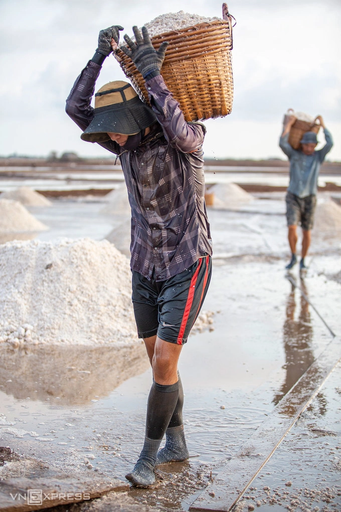 Ngoài xe đẩy, cần xé là dụng cụ thiết yếu để đựng muối trong quá trình thu hoạch. Mỗi cần xé muối có trọng lượng 40kg, đôi khi cần xé trượt xuống làm trầy vai người vác, muối xát vào da nhưng các diêm dân vẫn bám nghề.  “Người làm muối luôn cầu mong nắng gắt, trời thương cho nắng nhiều thì cào muối có lãi”, anh Lĩnh, người vác cần xé muối phía sau ảnh chia sẻ.