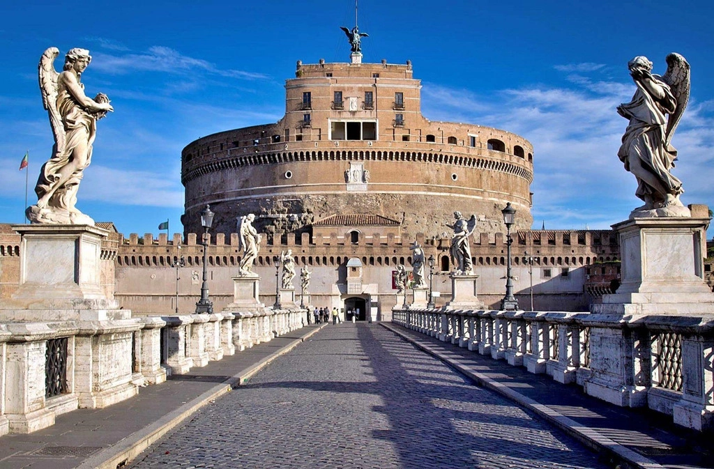 Lâu đài Sant'Angelo: Đến Vatican, bạn nhất định phải ghé thăm lâu đài San’tAngelo sừng sững bên dòng sông Tiber thơ mộng. Tòa lâu đài được xây dựng bởi kiến trúc sư Antonius Pius. Trước đây, công trình được sử dụng làm nhà tù quốc gia. Khi du lịch Vatican phát triển, nơi đây lại trở thành điểm tham quan hấp dẫn. Cây cầu Ponte San’tAngelo được bắc qua sông Tiber ngay phía trước tòa lâu đài khiến khung cảnh nơi đây càng thơ mộng, nhất là lúc hoàng hôn buông xuống. Ảnh: Delightfully Italy.