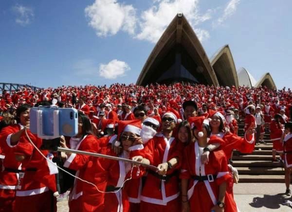 Tại trước khu vực nhà hát Opera, Sydney, Úc, hàng ngàn người trong trang phục ông già Noel chụp ảnh lưu niệm với “gậy tự sướng” sau khi hoàn thành cuộc chạy bộ tham gia gây quỹ từ thiện giúp đỡ trẻ em có hoàn cảnh khó khăn