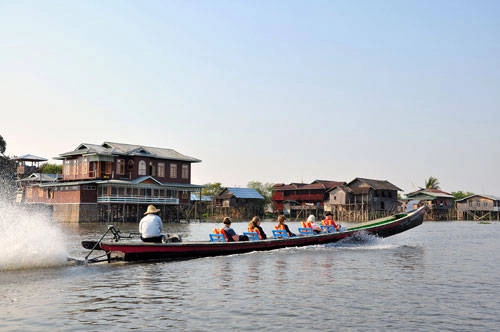 Một chiếc thuyền chở khách băng qua một dãy nhà hàng sang trọng lẫn căn chòi nghèo khổ của người dân trên hồ Inle