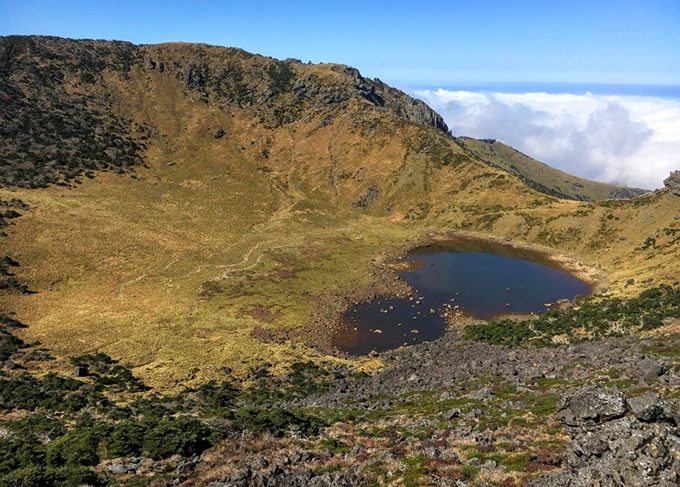 Hallasan vốn là ngọn núi lửa được hình thành từ hàng triệu năm trước nhưng đã ngừng hoạt động. Bao quanh là thảm thực vật, cảnh quan núi đồi, tạo nên hòn đảo Jeju nổi tiếng. Đỉnh Hallasan chính là "trái tim" của Jeju mà bất cứ du khách nào tới đây cũng muốn check in.
