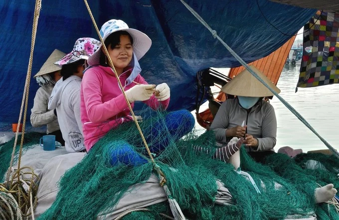 Trong khi đàn ông ra khơi, phụ nữ ở nhà làm nghề vá lưới thuê để có thu nhập, khoảng 100.000 đồng mỗi ngày công. Với những loại lưới mắt to, đồ nghề chỉ gồm móc lưới bằng nhựa giống chiếc ghim kẹp, con dao nhỏ và cuộn dây. “Chủ tàu nào thuê tôi cũng nhận, có khi không vá tại cảng mà phải lên thuyền đi cùng họ, lênh đênh trên những con sóng xa bờ”, một phụ nữ đã làm nghề 20 năm chia sẻ. Ảnh: Jean-noel Chatelain.