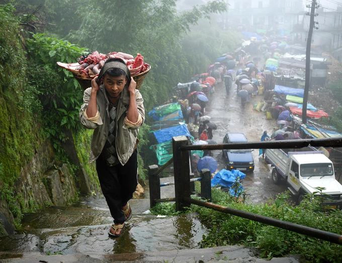 Winchester Lyngkhoi đang mang thịt tươi đến quầy hàng của mình vào ngày họp chợ. Khi được hỏi có gặp khó khăn vì sống ở một nơi nhiều mưa đến vậy, chàng trai 26 tuổi trả lời: "Chúng tôi không nghĩ về điều đó khi phải làm việc".