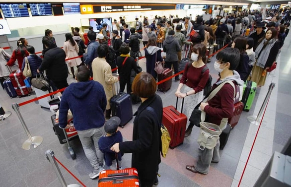 Các du khách xếp hàng chờ làm thủ tục tại sân bay Haneda, Nhật Bản - Ảnh: KYODO