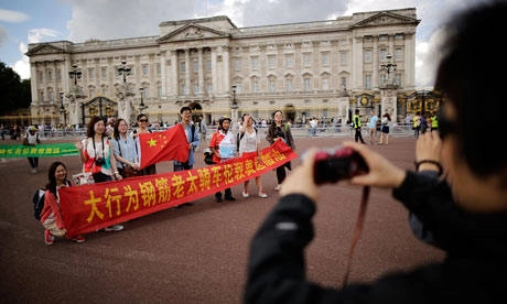 Chinese tourists have their pictures taken outside Buckingham Palace