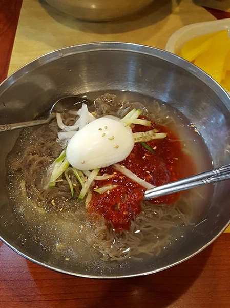 Để tách khỏi dòng người hối hả ấy, tôi chọn cho mình một quán nhỏ ven đường. Ở thành phố này, bạn có thể dễ dàng gặp những cửa hàng bán thức ăn truyền thống của hộ gia đình. Đó là những quán bán mì, thịt nướng hay gà hầm sâm. Đẩy cửa bước vào trong, bạn sẽ thấy một sự khác biệt: bên ngoài lạnh run - bên trong ấm áp, bên ngoài ồn ào - bên trong tĩnh lặng đến không ngờ. Người dân Hàn thân thiện nhưng không sõi tiếng Anh, vì thế tôi chọn món ăn bằng cách chỉ hình, vì tên món cũng viết bằng tiếng Hàn. Đó là món mì lạnh với thịt bò, kim chi, củ cải ăn kèm trứng và một ít đá bào. Khi nhìn thấy đá bào trong bát mì, tôi đã nghĩ tới một bát phở thịt bò cùng nước lèo nhưng lại có đá lạnh ăn như một món chè ngọt. Mì lạnh tương tự vậy khiến tôi lần đầu ăn rất vất vả vì không hợp vị. Nhưng với tôi, đây là một trải nghiệm thú vị. Để tách khỏi dòng người hối hả ấy, tôi chọn cho mình một quán nhỏ ven đường. Ở thành phố này, bạn có thể dễ dàng gặp những cửa hàng bán thức ăn truyền thống của hộ gia đình. Đó là những quán bán mì, thịt nướng hay gà hầm sâm. Đẩy cửa bước vào trong, bạn sẽ thấy một sự khác biệt: bên ngoài lạnh run - bên trong ấm áp, bên ngoài ồn ào - bên trong tĩnh lặng đến không ngờ. Người dân Hàn thân thiện nhưng không sõi tiếng Anh, vì thế tôi chọn món ăn bằng cách chỉ hình, vì tên món cũng viết bằng tiếng Hàn. Đó là món mì lạnh với thịt bò, kim chi, củ cải ăn kèm trứng và một ít đá bào. Khi nhìn thấy đá bào trong bát mì, tôi đã nghĩ tới một bát phở thịt bò cùng nước lèo nhưng lại có đá lạnh ăn như một món chè ngọt. Mì lạnh tương tự vậy khiến tôi lần đầu ăn rất vất vả vì không hợp vị. Nhưng với tôi, đây là một trải nghiệm thú vị.