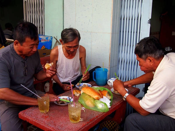 Những người đàn ông vừa ăn sáng vừa bàn chuyện. 