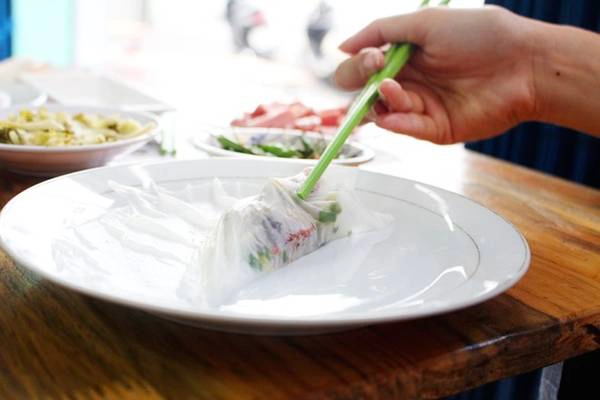 Thực khách cho nhân (thịt/nem nướng/nem chua) lên trên, thêm ít dưa cải, xoài xanh, dưa leo, rau thơm và cuốn lại thành một cuốn xinh xắn