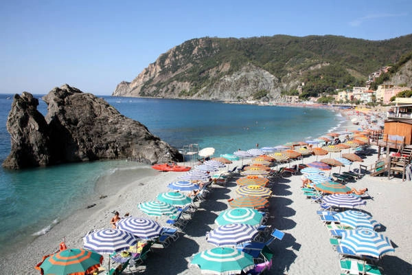 Bãi biển ở làng Monterosso tràn ngập những tán dù rực rỡ dưới nắng hè - Ảnh: linter.