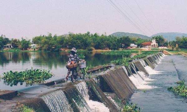 Đập Tam Giang nằm trên con đường nối giữa quốc lộ và nhà thờ Mằng Lăng. Khi từ quốc lộ vào, có lẽ bạn sẽ bị những bụi tre che khuất. Nhưng khi từ nhà thờ Mằng Lăng trở ra lại, bị sẽ dễ dàng bắt gặp con đập khá là rộng này. Người không quen khi bước ra đập rất dễ trợt té vì có rất nhiều rong rêu bấm rất trơn. Còn đối với người dân ở đây, chuyện đi lại qua đập hằng ngày là chuyện quá đỗi bình thường, mặc kệ rong rêu và dòng nước chảy xiết. 