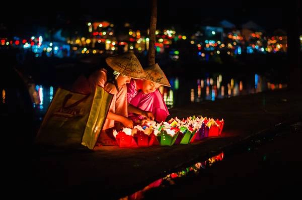 Hai bé mặc áo bà ba đội nón ngồi bán đèn hoa đăng ở Hội An. Ảnh: Tinhte.vn