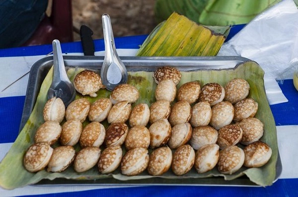 Khao Nom Krok trông như bánh căn Việt Nam, làm từ sữa dừa, đường, gạo nếp và bột mì. Ở miền Nam, món này ăn kèm với thịt heo băm nhỏ, chấm nước mắm chua ngọt - Ảnh: Matt Davies Khao Nom Krok trông như bánh căn Việt Nam, làm từ sữa dừa, đường, gạo nếp và bột mì. Ở miền Nam, món này ăn kèm với thịt heo băm nhỏ, chấm nước mắm chua ngọt - Ảnh: Matt Davies