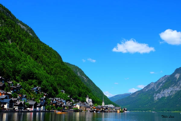 Có ít nhất 3 cách từ Salzburg (quê hương của Mozart) đến Hallstatt, nhưng chúng tôi chọn việc di chuyển kết hợp giữa bus và tàu. Trên chiếc xe bus 150 từ Salzburg, các bạn đừng vội tựa ghế mà ngủ thiếp đi, như vậy sẽ lãng phí khung cảnh yên ả hai bên đường đi! Có khá nhiều khu làng ẩn khuất sau hồ, hoặc đột nhiên một ngôi nhà nhỏ xuất hiện ở lưng chừng đồi trên nền cỏ xanh mướt, hoặc giữa một thảm hoa cải vàng, chắc chắn khiến bạn mê mệt.