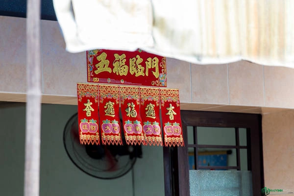 Phía trước một số gia đình có dán miếng giấy đỏ với hàng chữ Hoa màu vàng nổi bật.