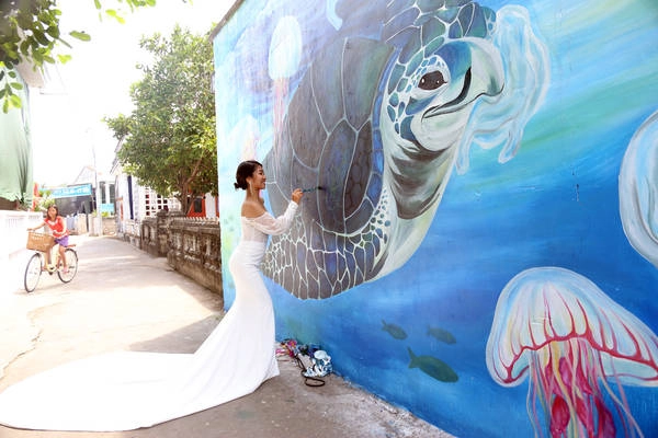 Bích hoạ "Nói Không Với Túi Ni Lông" của hoạ sĩ Trang. Sắp tới, Trang sẽ lên xe hoa. Cùng với mong muốn đóng góp công sức của mình cho dự án, Trang đã tình nguyện đến đảo vẽ đồng thời chụp ảnh cưới tại chính tác phẩm của mình. Ảnh: Nguyễn Hồng Minh Bích hoạ "Nói Không Với Túi Ni Lông" của hoạ sĩ Trang. Sắp tới, Trang sẽ lên xe hoa. Cùng với mong muốn đóng góp công sức của mình cho dự án, Trang đã tình nguyện đến đảo vẽ đồng thời chụp ảnh cưới tại chính tác phẩm của mình. Ảnh: Nguyễn Hồng Minh