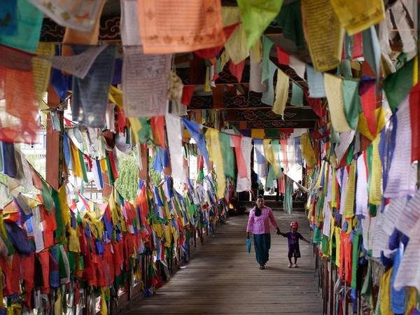 Người mẹ và con trai đi qua cây cầu treo kín cờ cầu nguyện. Khoảng 75% dân số Bhutan theo Phật giáo dòng Kim Cương Thừa. Người mẹ và con trai đi qua cây cầu treo kín cờ cầu nguyện. Khoảng 75% dân số Bhutan theo Phật giáo dòng Kim Cương Thừa.