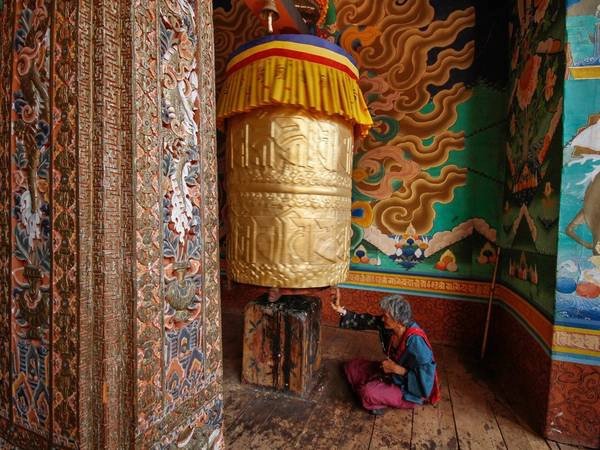 Bao quanh là những bức tranh Phật giáo đầy màu sắc, một cụ già quay kinh luân (bánh xe cầu nguyện) ở ngôi đền tại Punakha, phía tây Bhutan. Các kinh luân được chạm trổ tỉ mỉ với hàng nghìn câu thần chú. Người địa phương cho rằng quay bánh xe cũng như đọc những thần chú này hàng nghìn lần. Bao quanh là những bức tranh Phật giáo đầy màu sắc, một cụ già quay kinh luân (bánh xe cầu nguyện) ở ngôi đền tại Punakha, phía tây Bhutan. Các kinh luân được chạm trổ tỉ mỉ với hàng nghìn câu thần chú. Người địa phương cho rằng quay bánh xe cũng như đọc những thần chú này hàng nghìn lần.