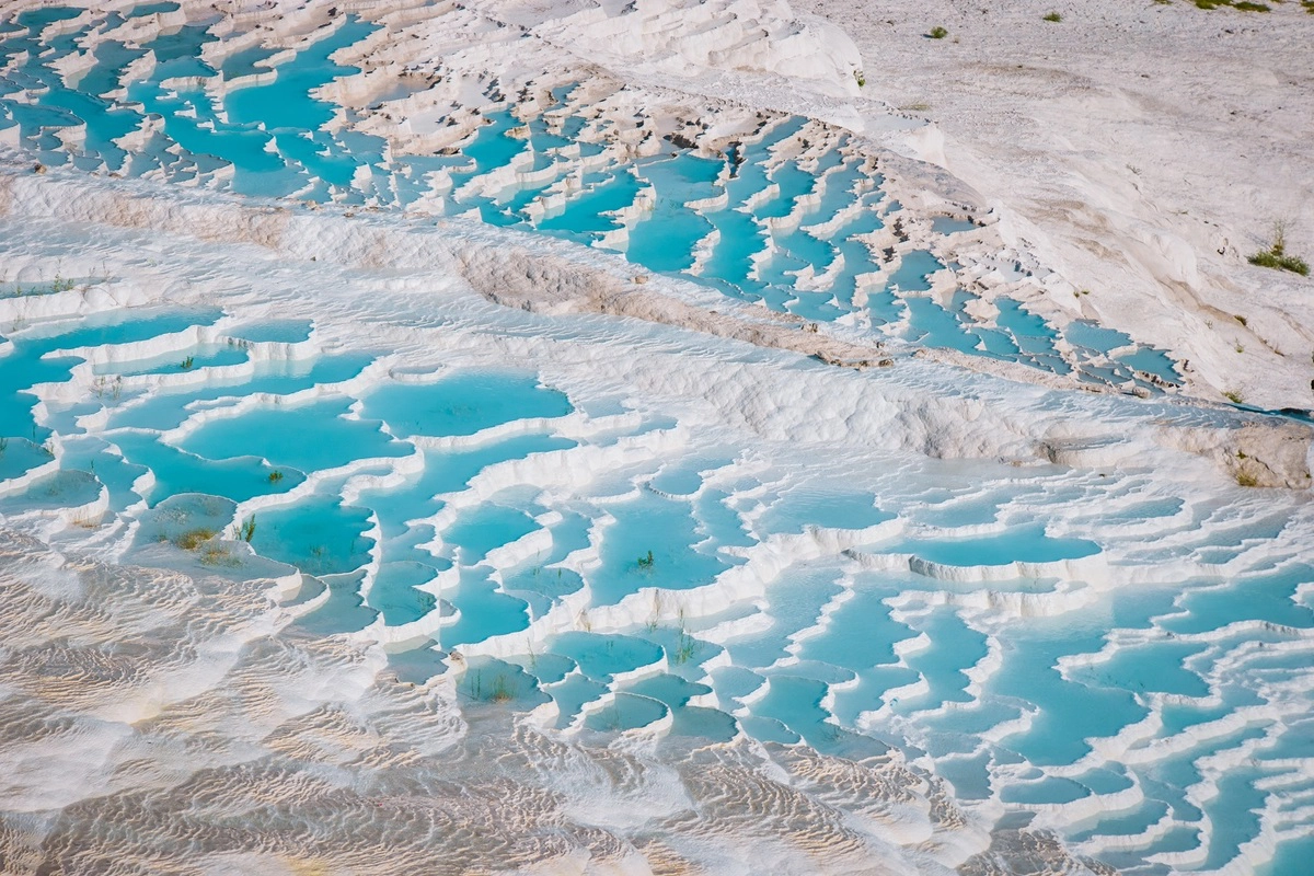 Pamukkale, hay Lâu đài bông trong tiếng Thổ Nhĩ Kỳ, là khu vực địa chất tự nhiên, nằm ở phía nam vùng Aegean, cách thành phố Denizli khoảng 20 km và thị trấn du lịch Kusadasi khoảng 2,5 giờ lái xe.   Khu vực được hình thành từ những con suối địa nhiệt, trên vách đá cao khoảng 200 m, nhìn xuống đồng bằng Cürüksu. Qua hàng nghìn năm, canxi cacbonat trong dòng nước được lắng đọng dưới dạng đá khoáng, tạo thành vách đá vôi trắng xóa. Trên đó là những hồ bơi tự nhiên hình bậc thang. Ảnh: Fokke Baarssen/Shutterstock.