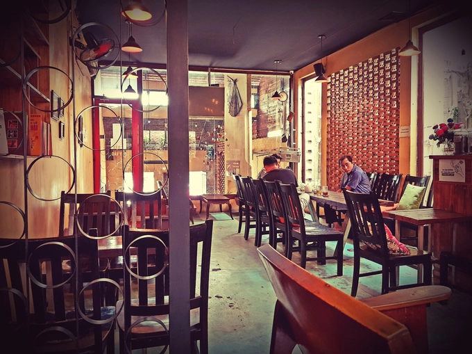 Nội thất quán tinh giản, kết hợp hài hòa giữa lớp sơn màu vàng phủ tường và bức tường gạch, khung cửa sắt. Các bộ bàn ghế có hai màu cơ bản: cam và đen. Tất cả được phủ một lớp vecni sáng bóng. Anh Văn kể có những chú, bác lớn tuổi nhà gần rất thích hẹn bạn đến đây bàn công việc hay chơi cờ tướng. Nội thất quán tinh giản, kết hợp hài hòa giữa lớp sơn màu vàng phủ tường và bức tường gạch, khung cửa sắt. Các bộ bàn ghế có hai màu cơ bản: cam và đen. Tất cả được phủ một lớp vecni sáng bóng. Anh Văn kể có những chú, bác lớn tuổi nhà gần rất thích hẹn bạn đến đây bàn công việc hay chơi cờ tướng.
