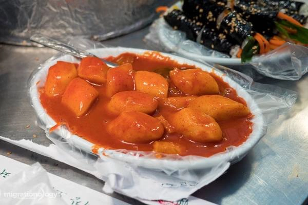 Tteokbokki hay bánh gạo cũng là món ăn đường phố phổ biến ở Hàn Quốc và du khách có thể tìm mua ở rất nhiều chỗ trong chợ. Những chiếc bánh gạo mềm được hầm chung với sốt ớt màu đỏ nổi bật rất thu hút giới trẻ. Món ăn này ngon nhất khi thưởng thức nóng, vừa khi mới lấy ra đĩa. 