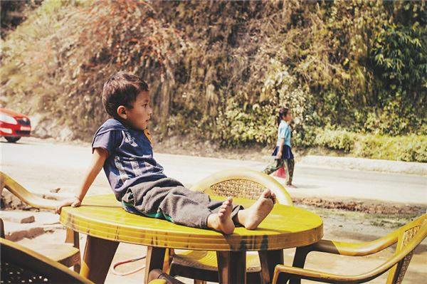 Bức ảnh được tác giả chụp trên đường đi từ Kathmandu đến một ngọn núi, tác giả dừng lại bên một cửa hàng ven đường để mua nước và đã chụp được “khoảng khắc vô tư” của cậu bé đang ngồi trên bàn.