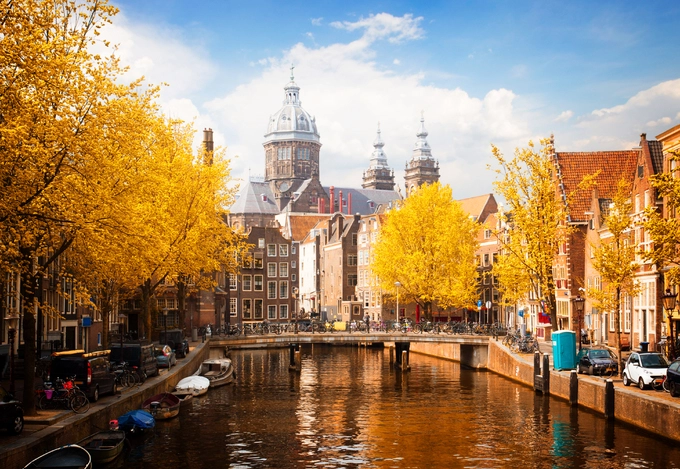 Amsterdam, Hà Lan  Với hơn 400.000 cây xanh trên khắp thành phố, Amsterdam là một trong những điểm đến đẹp nhất để ngắm cảnh sắc mùa thu. Từ tháng 9 đến tháng 11, các công viên, kênh đào lịch sử ở đây chìm trong sắc vàng đỏ của cây lá. Ngoài ra, những con đường trải đầy lá khô cũng làm khung cảnh trở nên lãng mạn hơn. Vào mùa thu, ở đây diễn ra một số lễ hội như Halloween, bảo tàng dưới trăng Museum Night. Ảnh: Dreams Time.