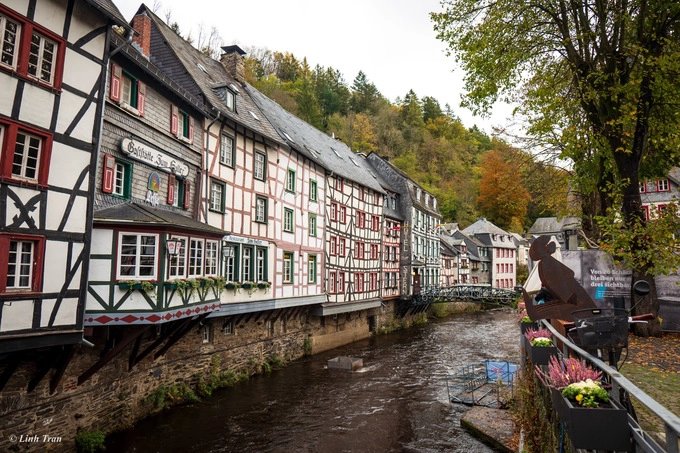 Rời Lübbennau, chúng tôi đến Aachen, thành phố thuộc bang Nordrhein – Westfalen. Cả nhóm đi xe hết gần 60 phút, hoặc trekking qua các ngôi làng tuyệt đẹp thuộc vùng rừng quốc gia Eifel sẽ tới Monschau, thị trấn cực tây của nước Đức nằm giáp biên giới Bỉ và Hà Lan.  Hơn 300 nếp nhà khung gỗ (Fachwerkhaus) nằm trong thung lũng bên dòng sông Rur, những con đường đá cuội nhỏ xíu, những ngõ nhỏ hun hút một người đi, kéo mắt nhìn về những cánh rừng đang vàng dần theo tiếng gọi của mùa. Tất cả mang lại cho Monschau một không khí huyền ảo, mơ màng của câu chuyện cổ tích.