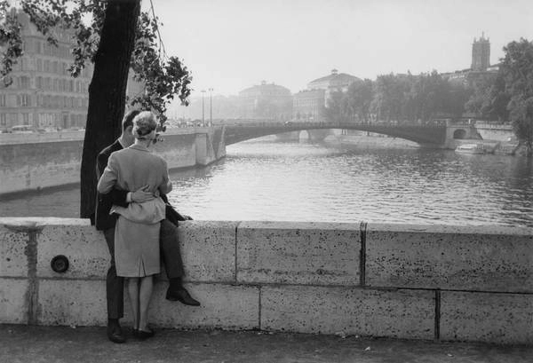 Cặp đôi đang ôm nhau tình tự bên cạnh một trong những chiếc cầu ở Paris Cặp đôi đang ôm nhau tình tự bên cạnh một trong những chiếc cầu ở Paris