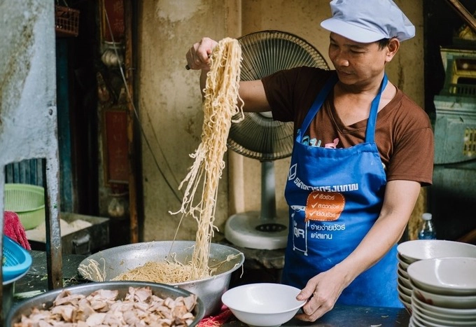 Đây không phải địa chỉ dành cho người ưa sạch sẽ bởi bếp nấu, chỗ ngồi đều rất đơn giản, thậm chí trông không mấy vệ sinh. Nhiều năm qua, khách hàng quen thuộc của họ là những người ít tiền. Quán không có tên, còn "Ba mee jub kang" do khách tự đặt cho dễ hỏi đường. "Ba mee" trong tiếng Thái có nghĩa là "mì trứng vàng" còn "Jub kang" chỉ những người lao động chân tay làm việc chăm chỉ.