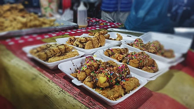Chuối chiên phủ cốm là biến tấu lạ cho món quà vặt quen thuộc ở Bazar. Chuối dùng để chiên có độ săn, sần sật như chuối sáp. Món ăn này không có độ giòn như chuối chiên Việt Nam. Giá một phần là 2 RM (11.000 đồng). Món ăn vặt ngon, rẻ ở chợ đêm Langkawi Chuối chiên phủ cốm là biến tấu lạ cho món quà vặt quen thuộc ở Bazar. Chuối dùng để chiên có độ săn, sần sật như chuối sáp. Món ăn này không có độ giòn như chuối chiên Việt Nam. Giá một phần là 2 RM (11.000 đồng). Món ăn vặt ngon, rẻ ở chợ đêm Langkawi